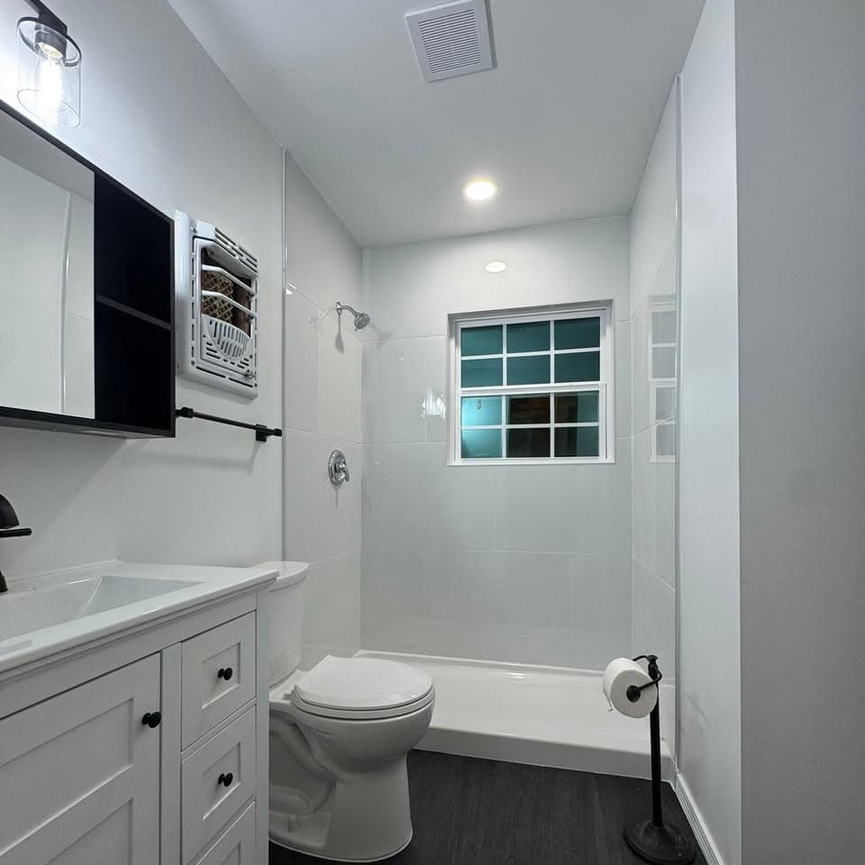 Finished bathroom with tiled tub surround and dark fixtures